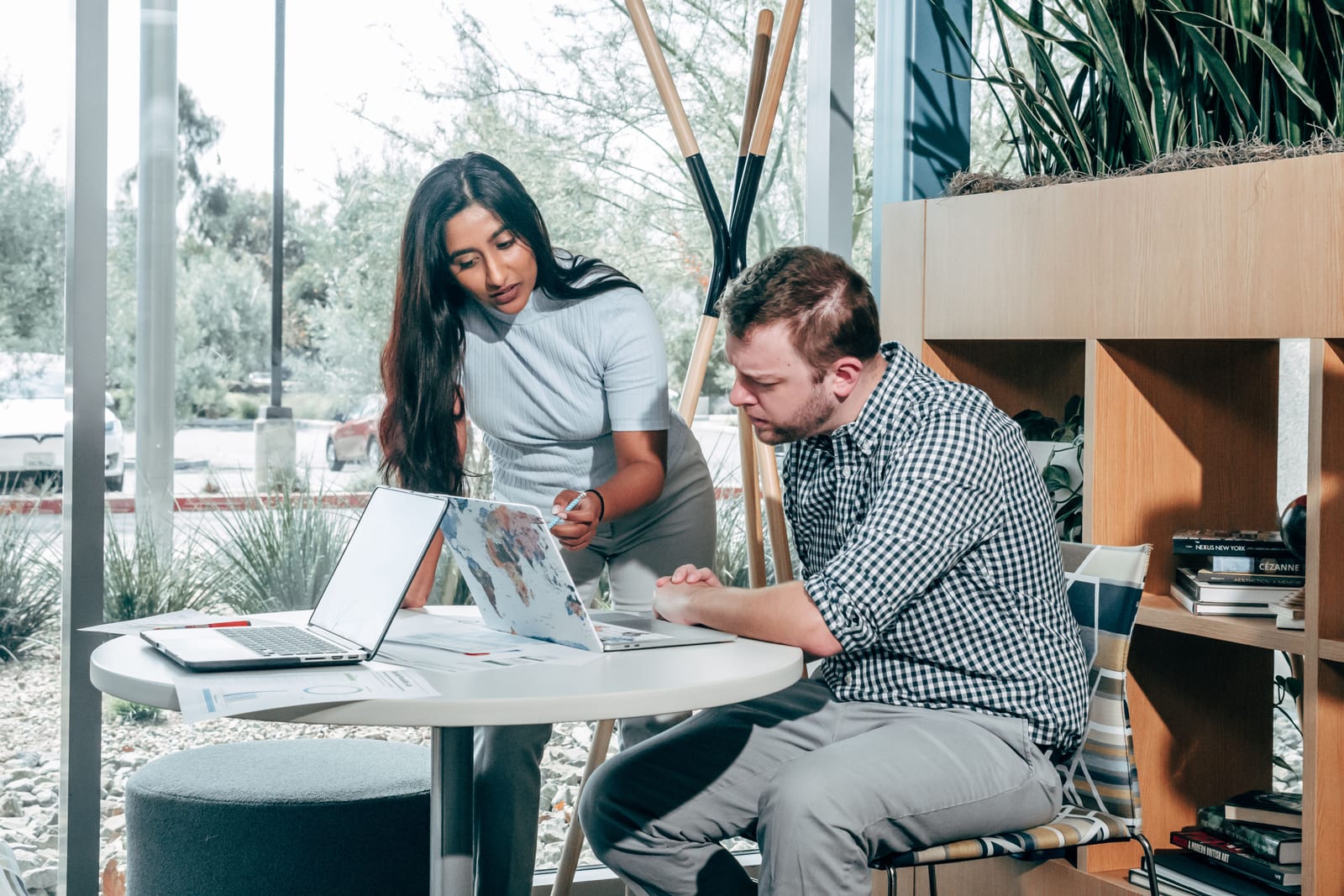 Two colleagues reviewing a laptop and project notes