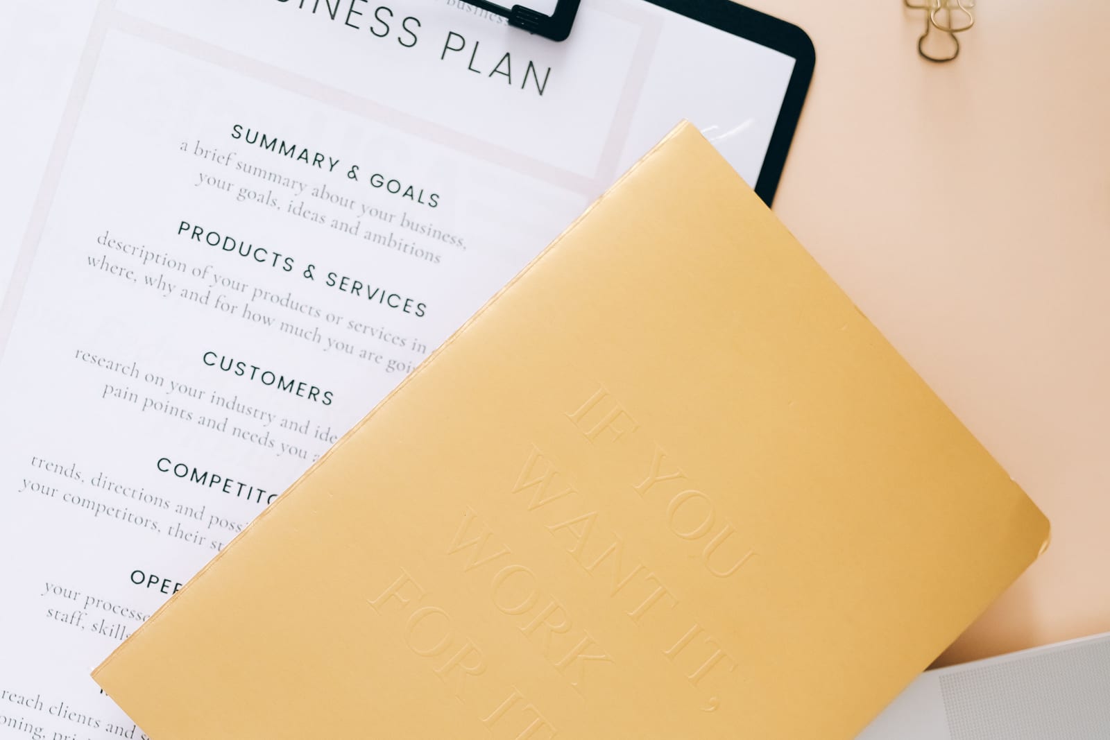 A business planning document beside a laptop and stationery